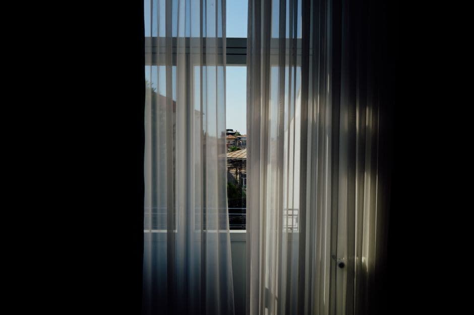 A sunny urban view through sheer window curtains