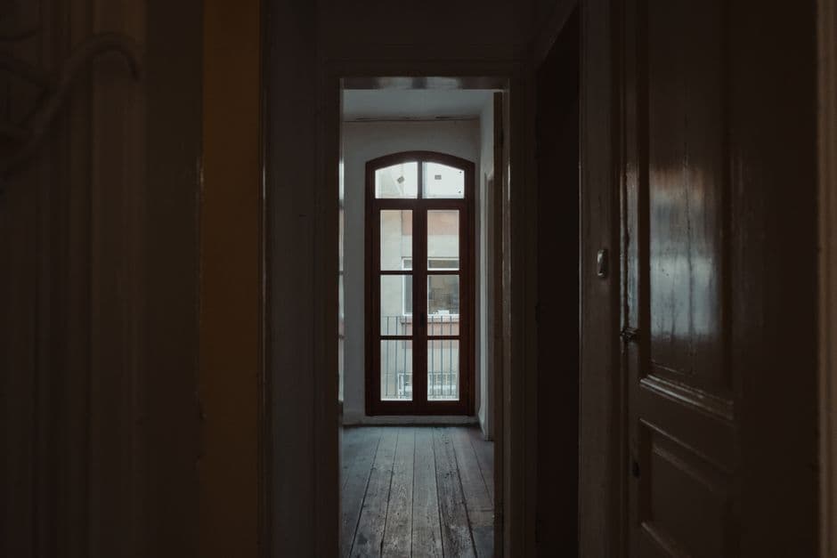 A dim hallway in a house with a window at the end
