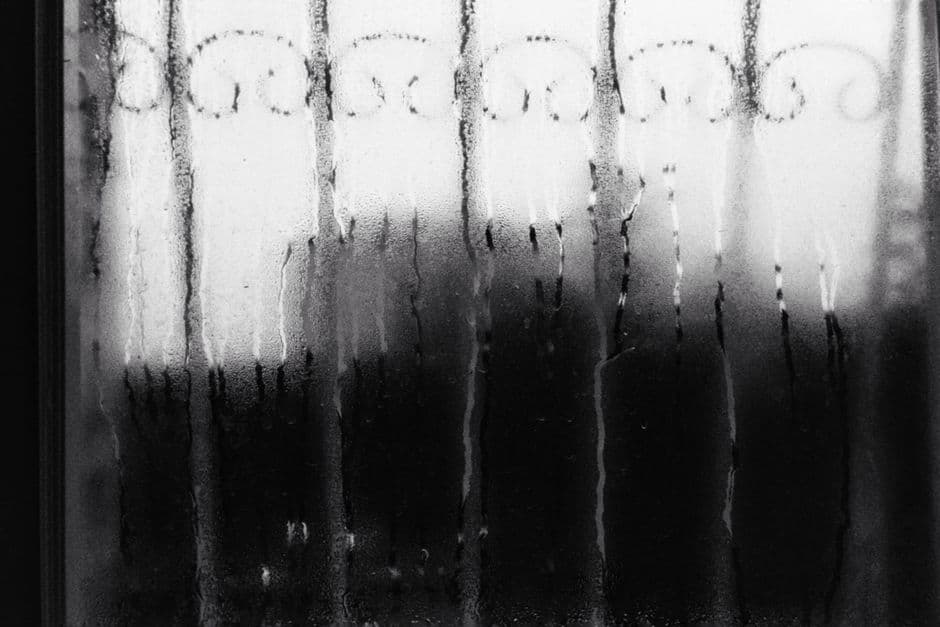 Condensation beaded on a dark window pane