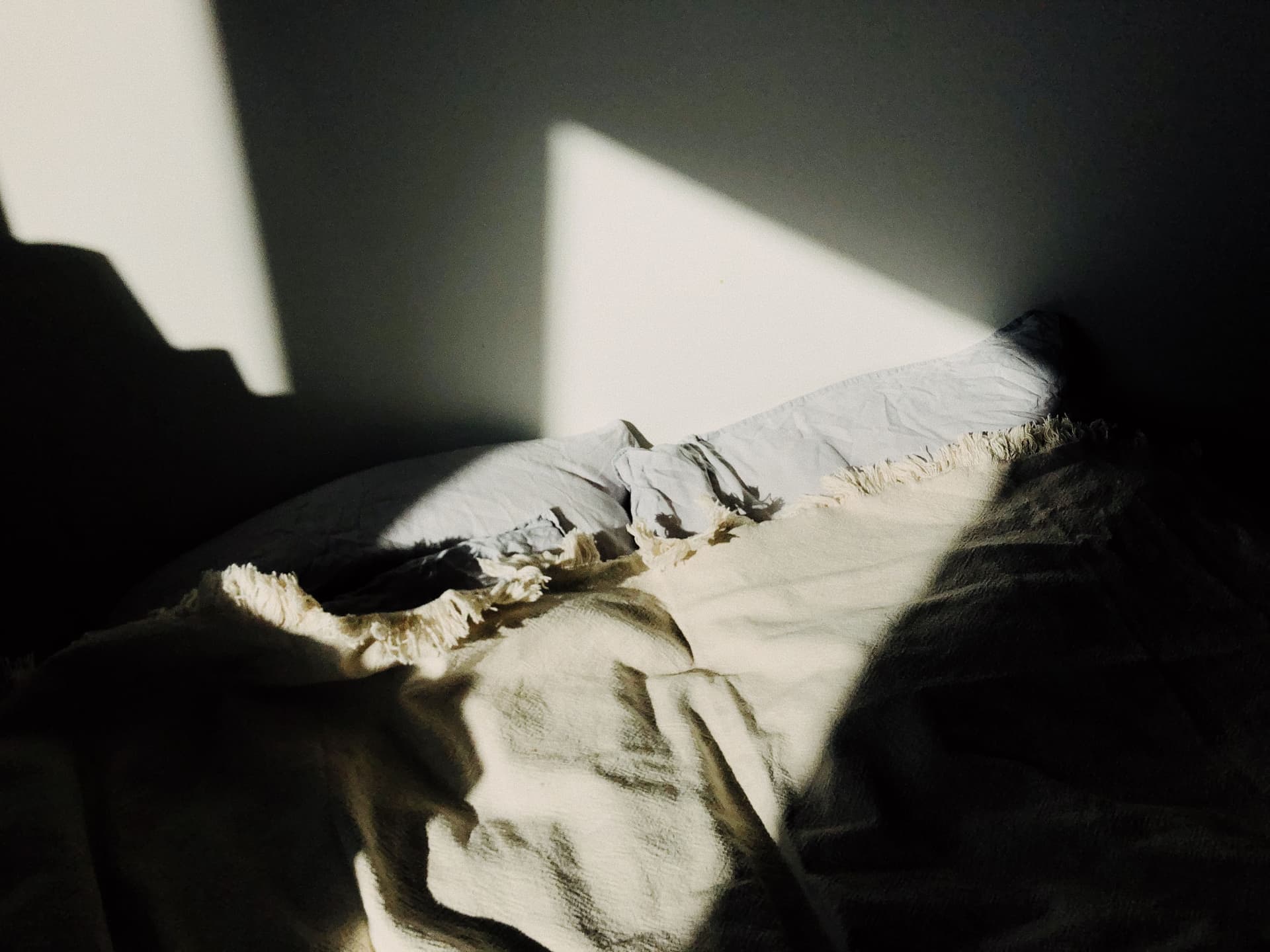 Sunlight falling across a bed and rumpled linen in a warm bedroom