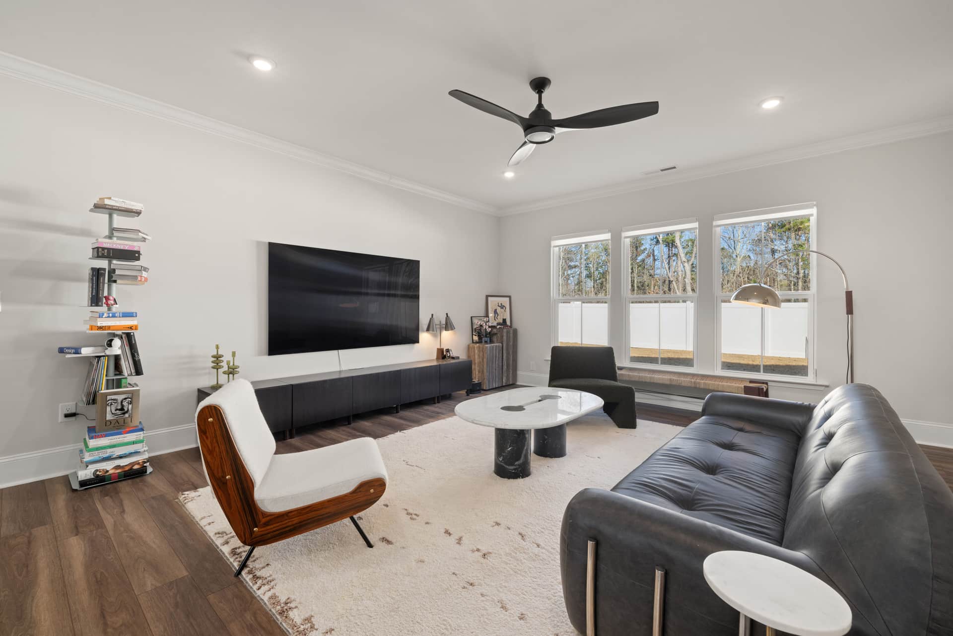 A minimal modern fan standing on a side table in a bright room