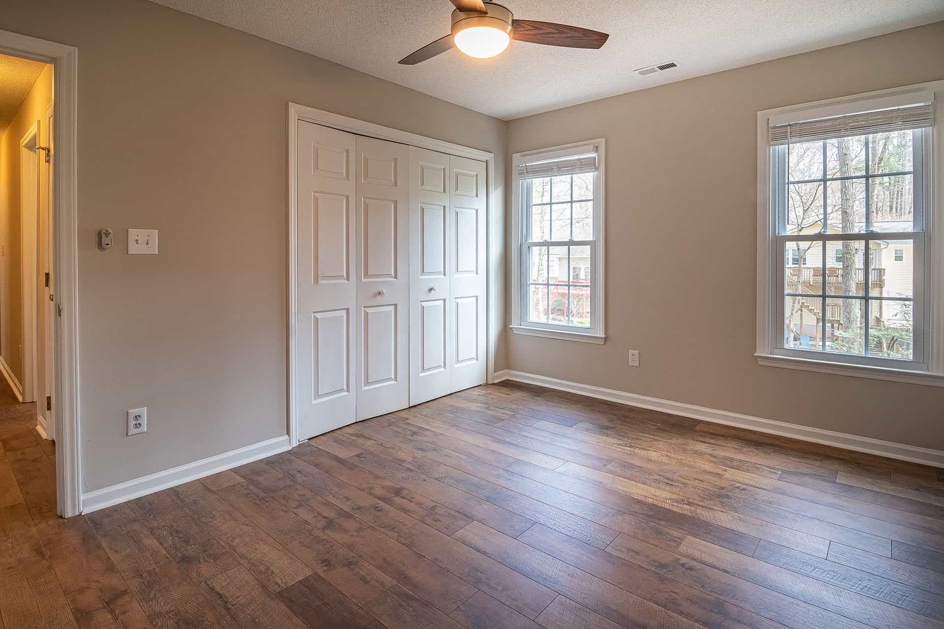 A square box fan standing on a wooden floor by a wall
