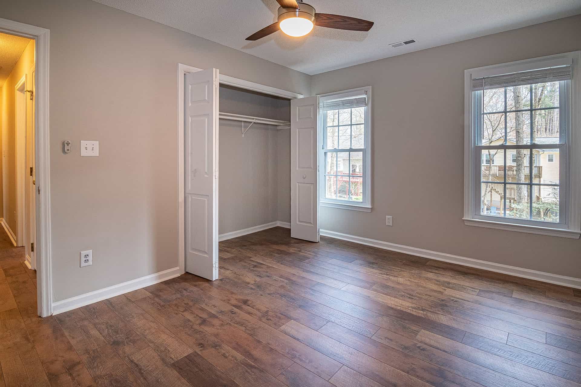 A ceiling fan turning against a white ceiling in a bright room