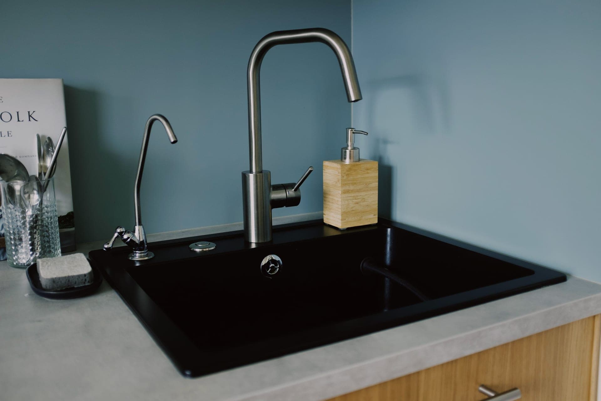A kitchen sink with a faucet in a minimalist setting