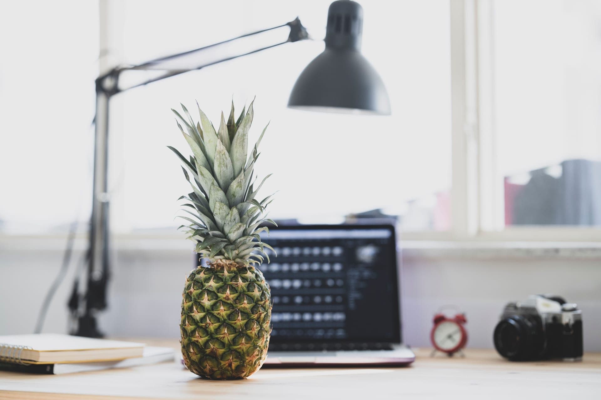 A small desk fan on a wooden desk beside a laptop