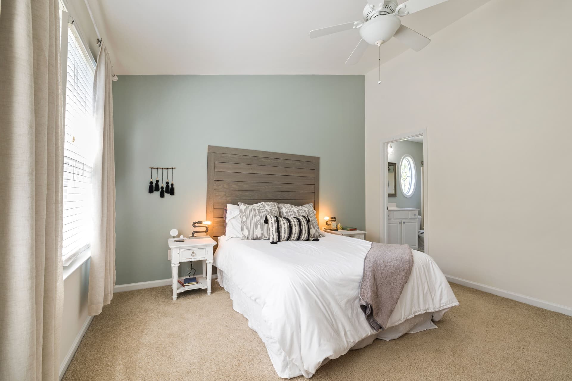 A tall slim tower fan standing beside a bed in a quiet bedroom