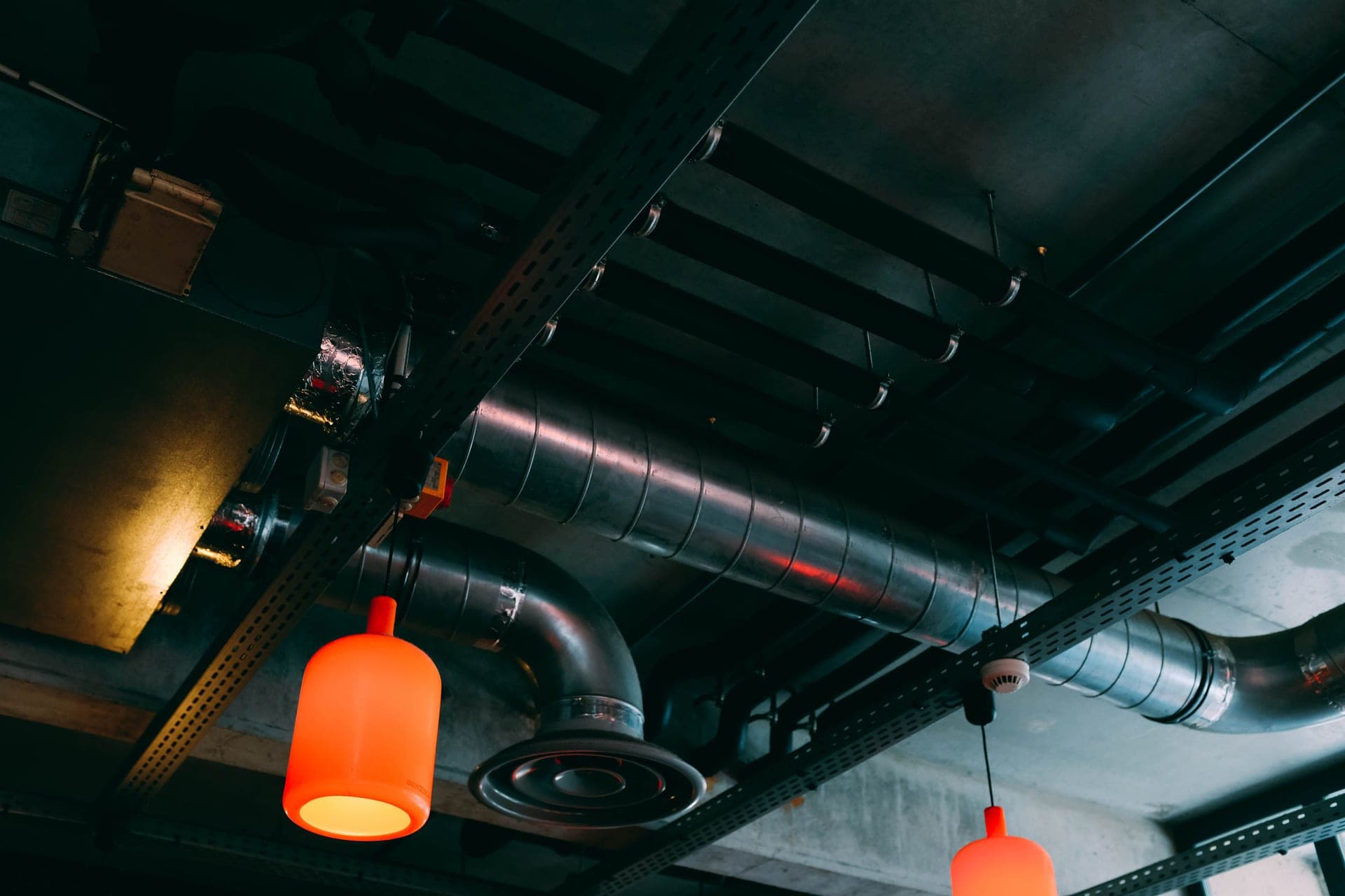 A modern industrial ceiling with exposed ducts and lamps