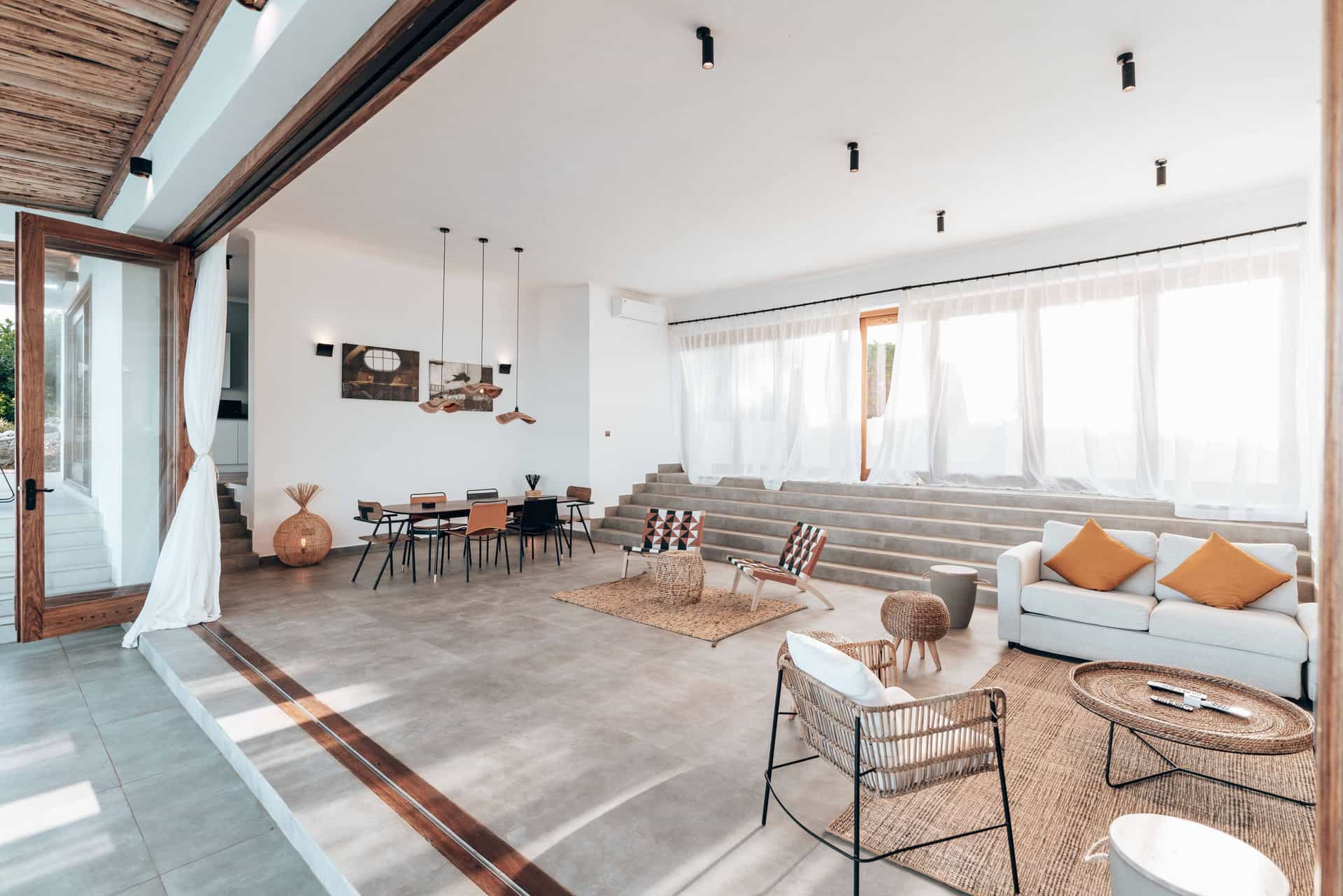 A large open-plan living room with tall windows and daylight