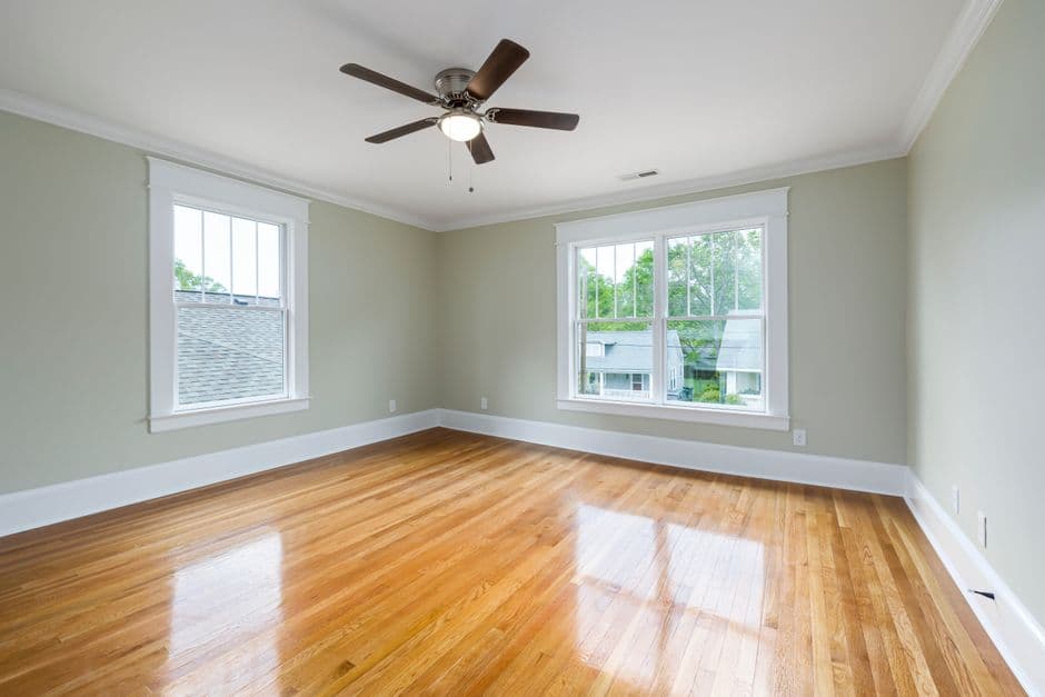 A bright empty room with wooden floors and a large window