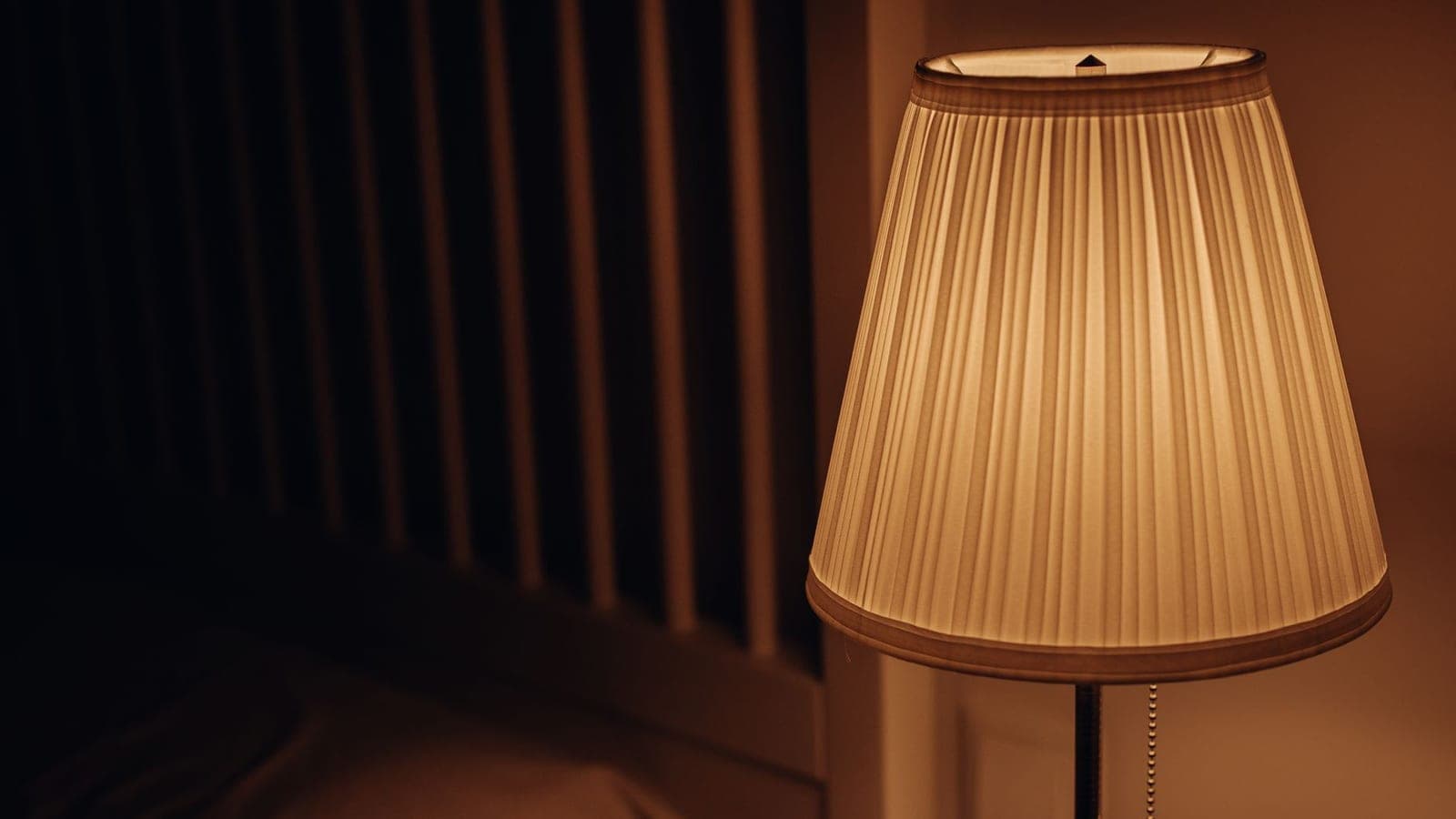 A dark bedroom with a lamp