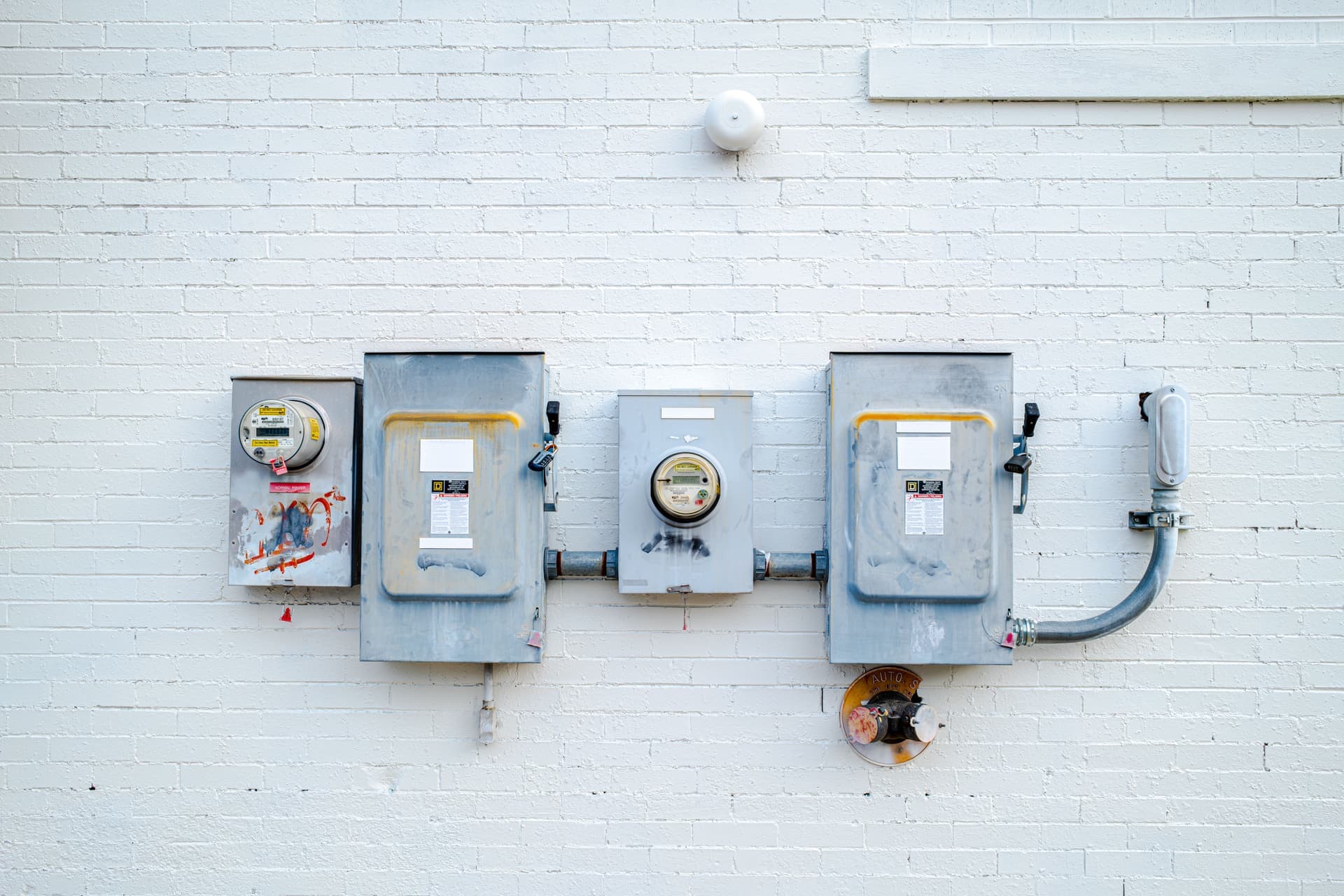 Electrical boxes and power meters on a white brick wall
