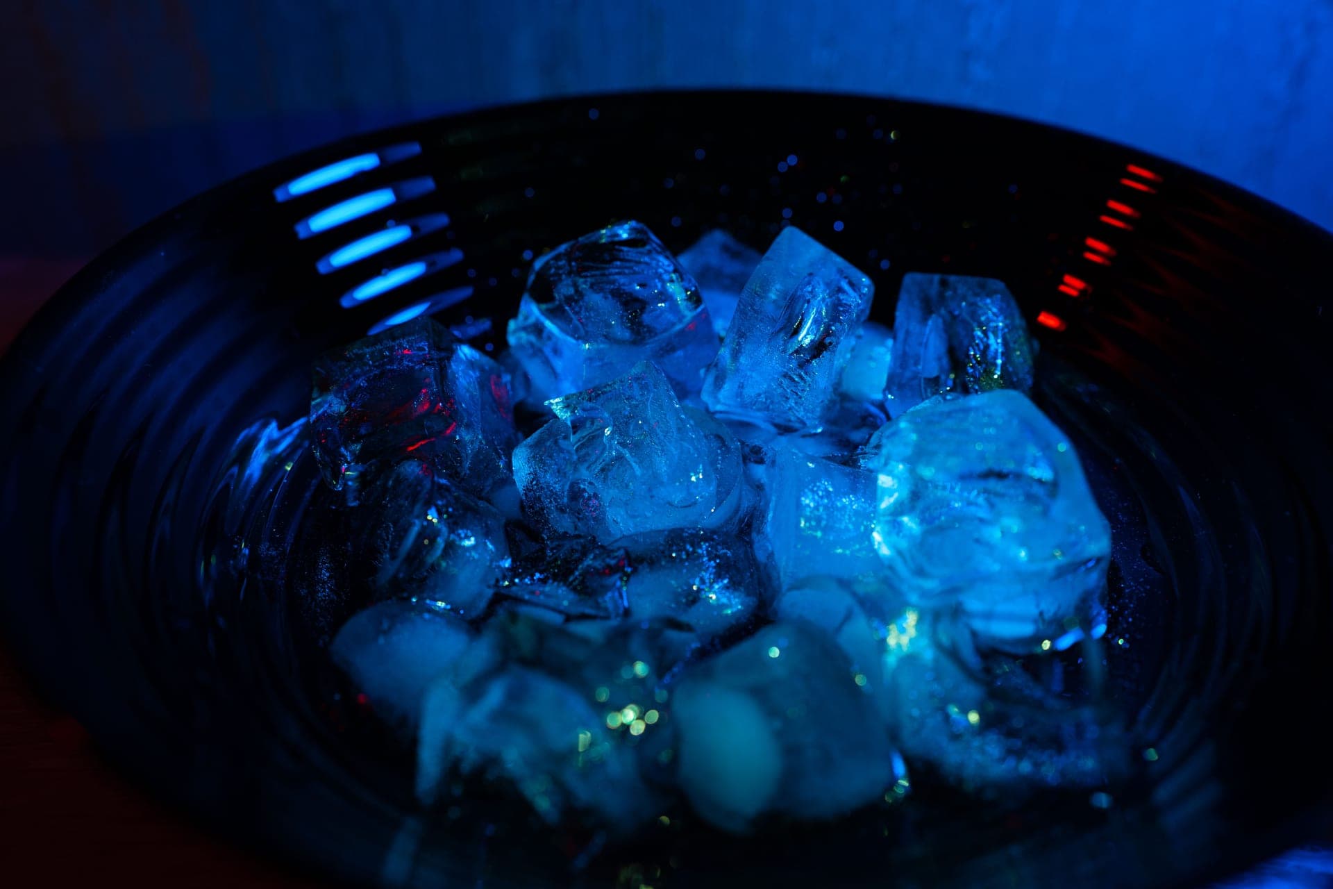 Ice cubes in a bowl lit with blue and red light