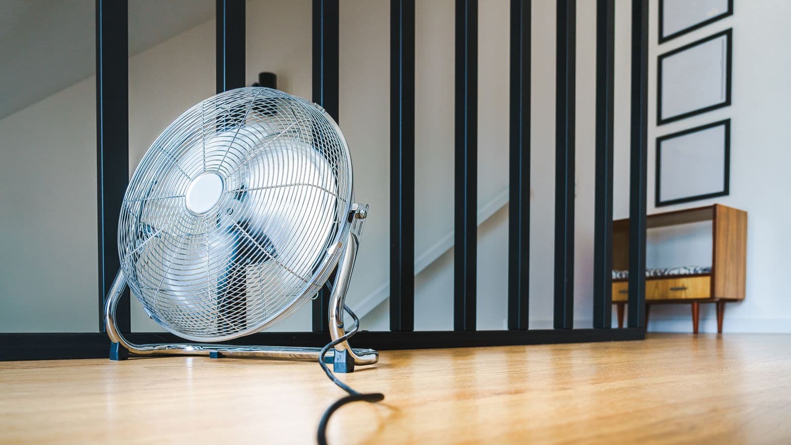 A floor-standing electric fan on a wooden floor in a modern room
