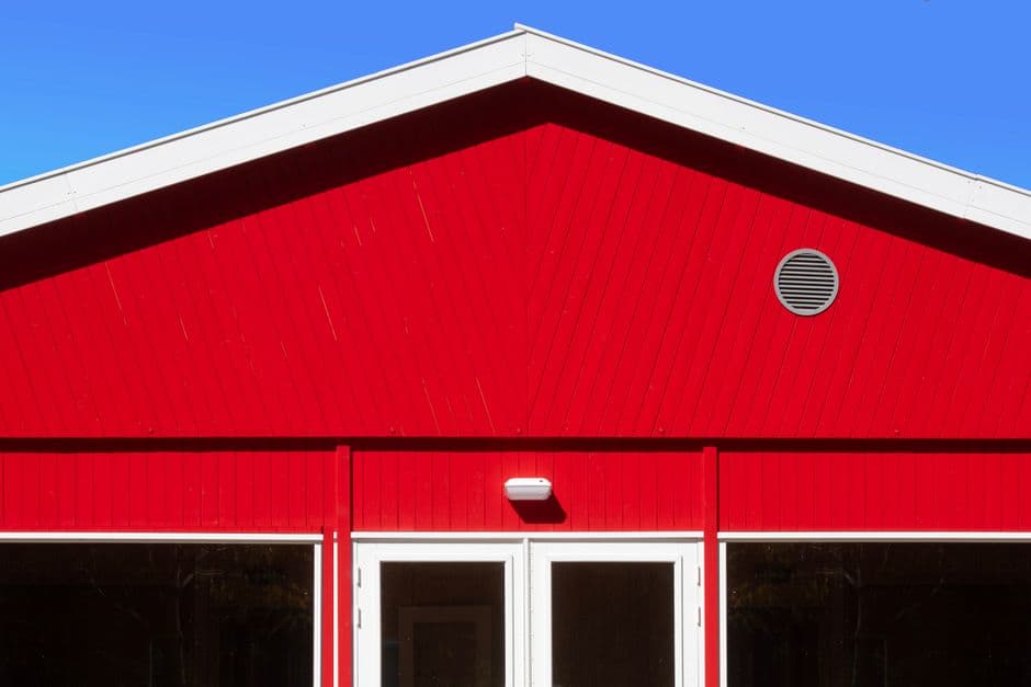 The gable end of a red barn-style building against a blue sky