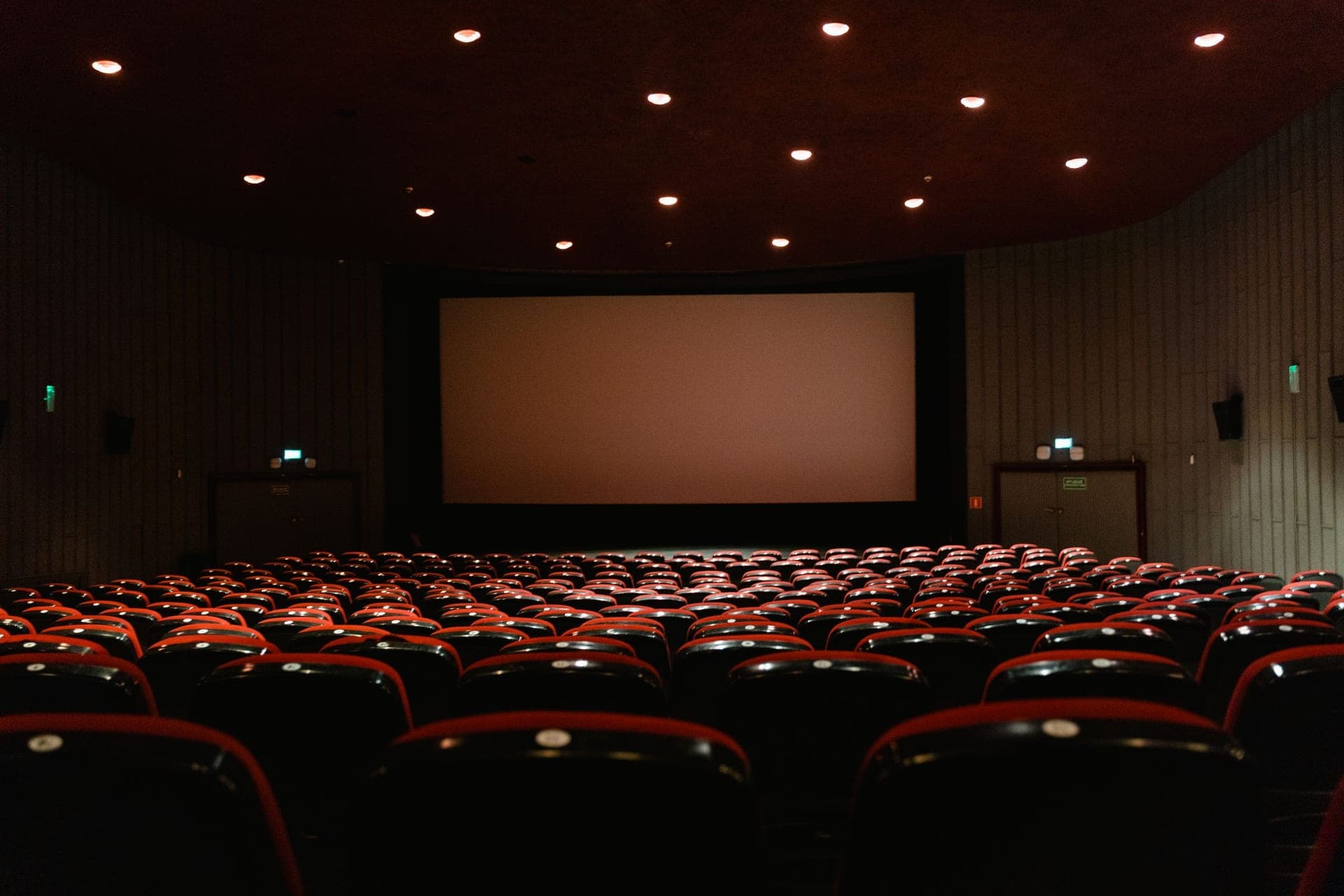 A darkened cinema room with rows of seats facing a large screen