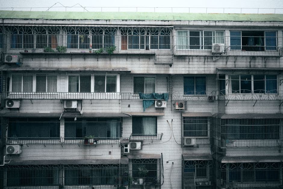 Air conditioners mounted in the windows of an apartment block