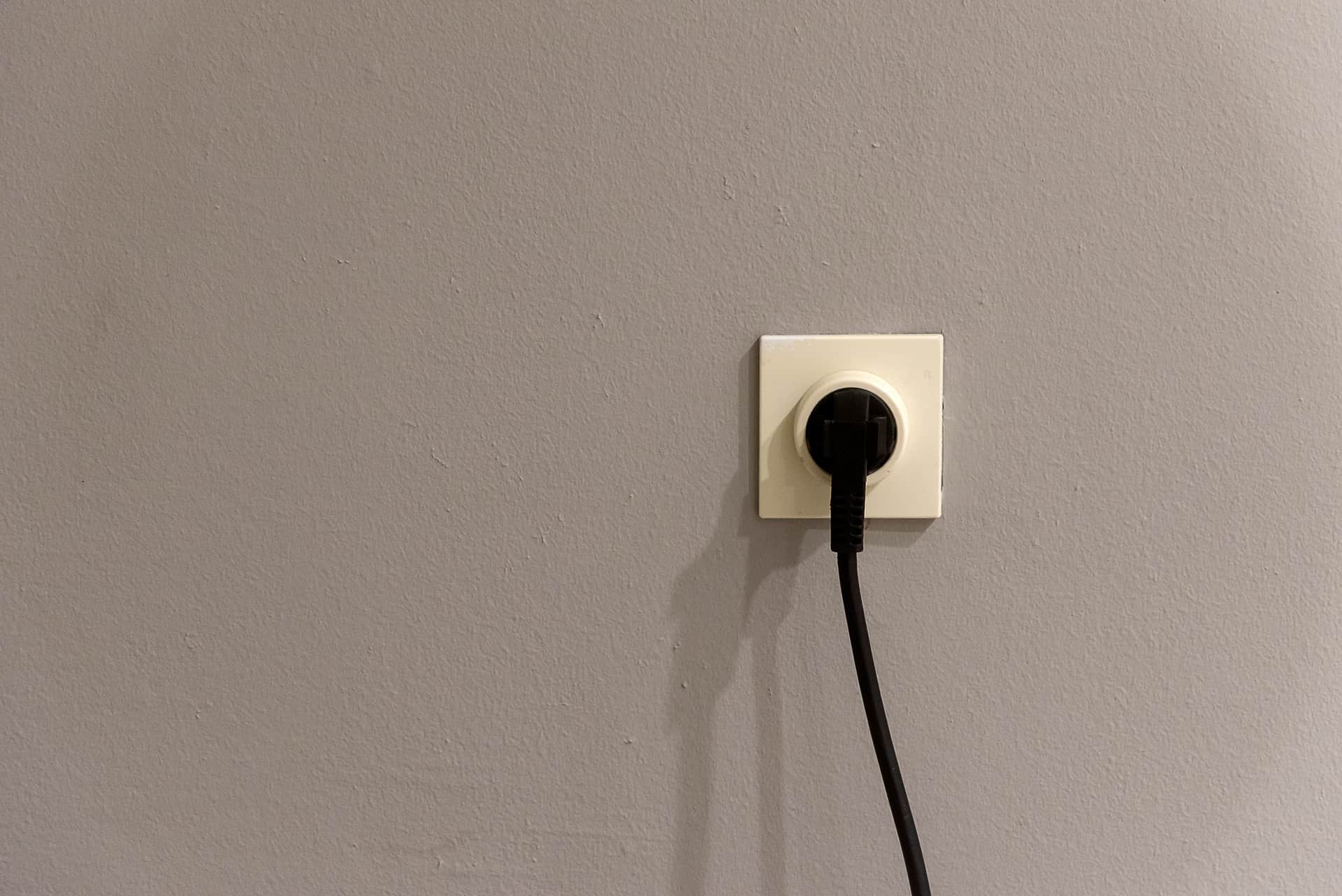 A plug in a wall outlet beside a baseboard in a domestic room