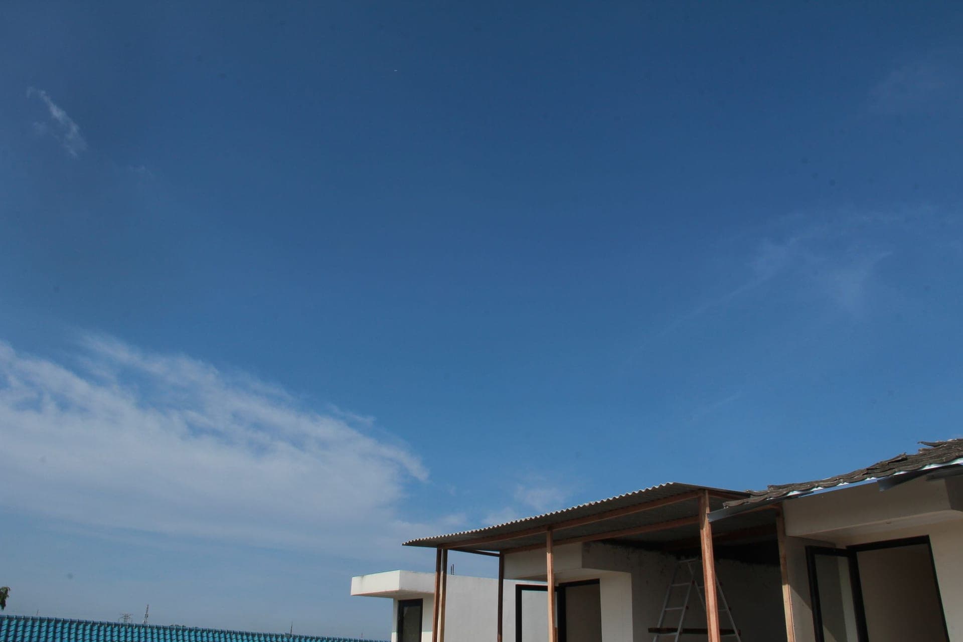 A plain building elevation against a bright clear summer sky