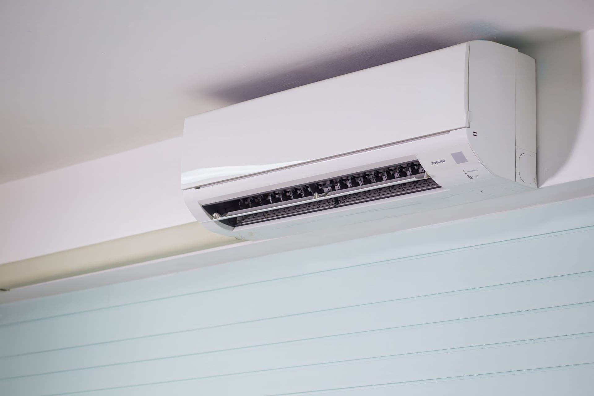 A wall-mounted mini-split indoor unit near the ceiling of a room
