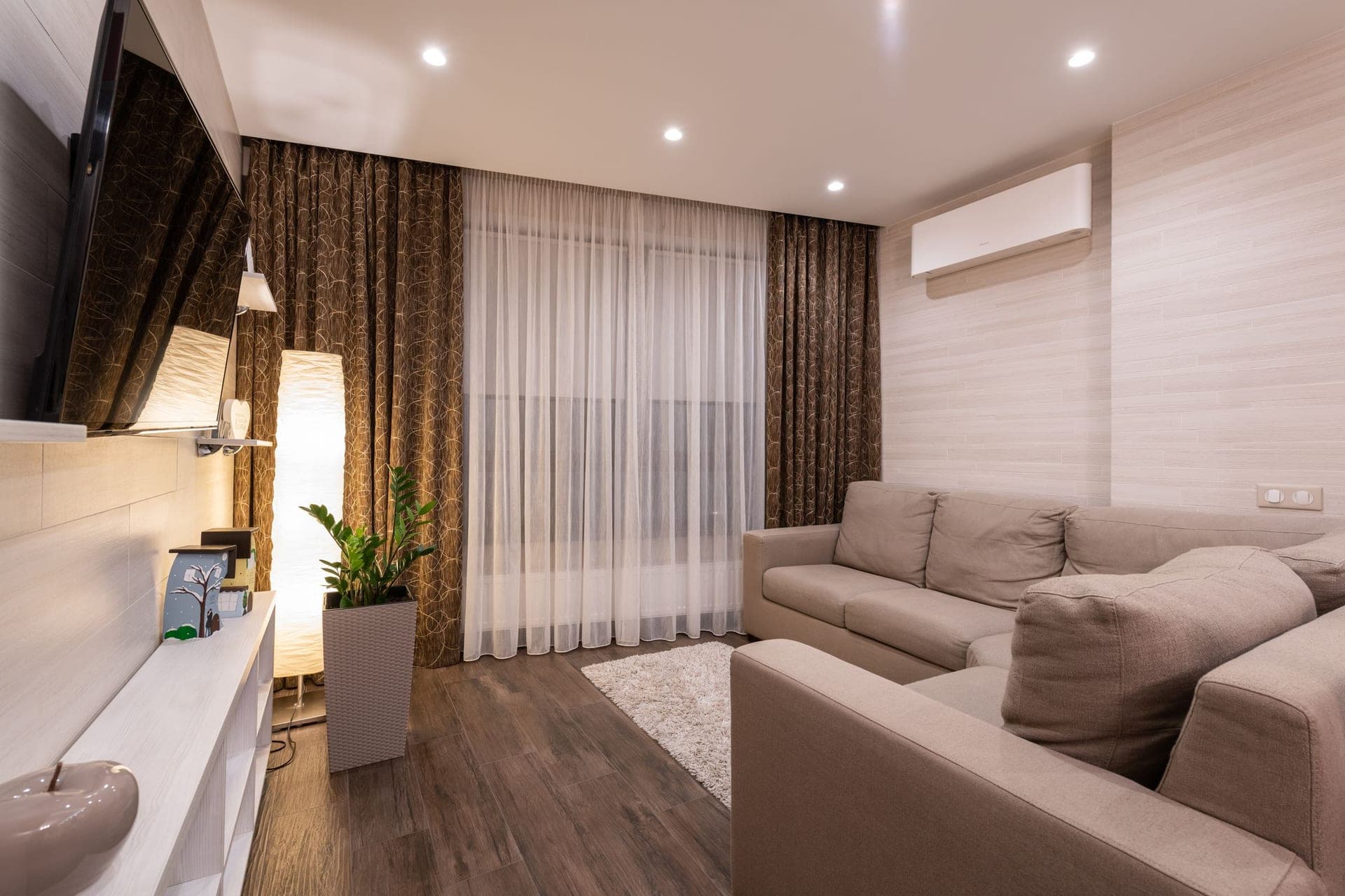 A living room with a sofa, wooden flooring and soft lighting