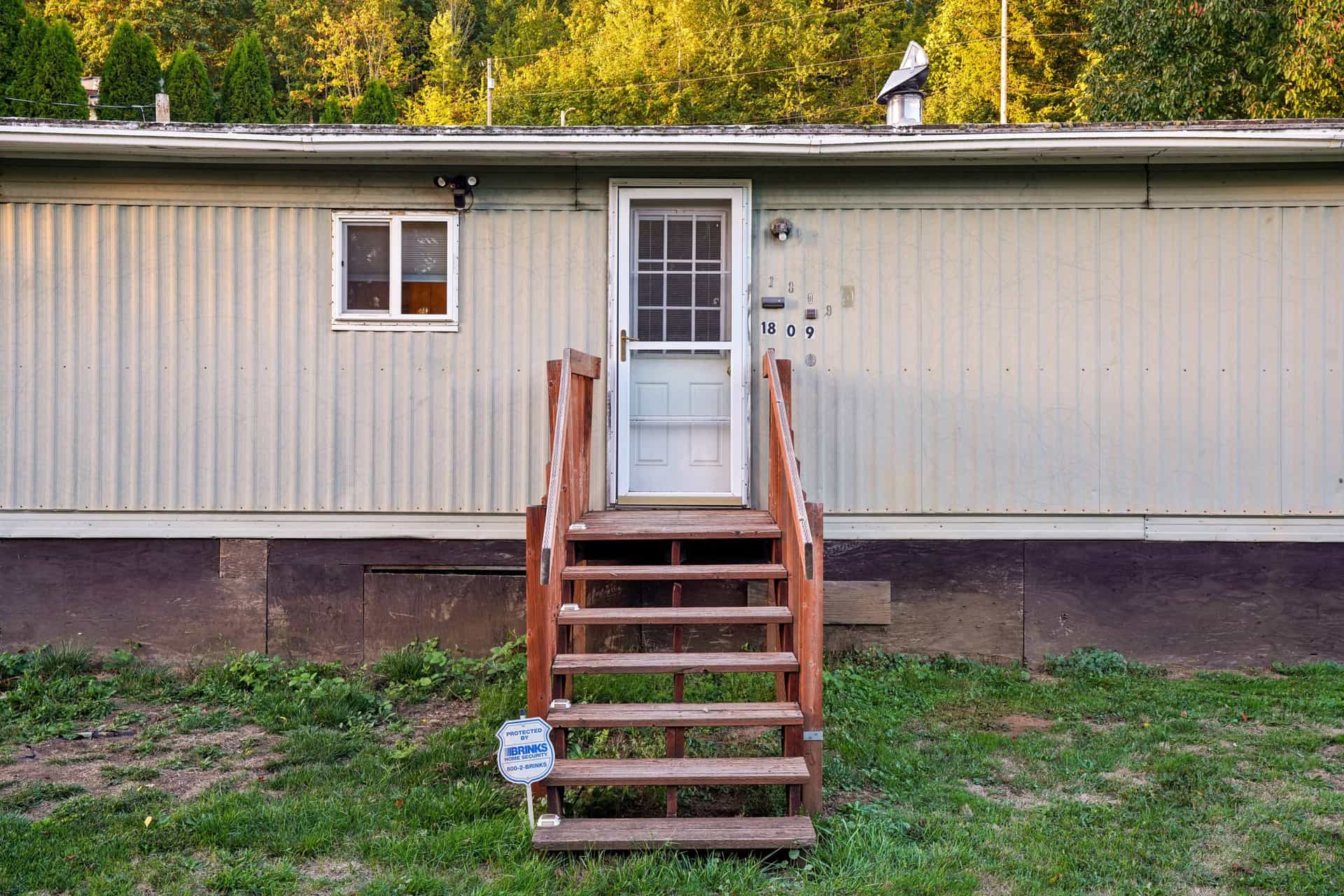 The exterior of a mobile home with wooden steps on a sunny day
