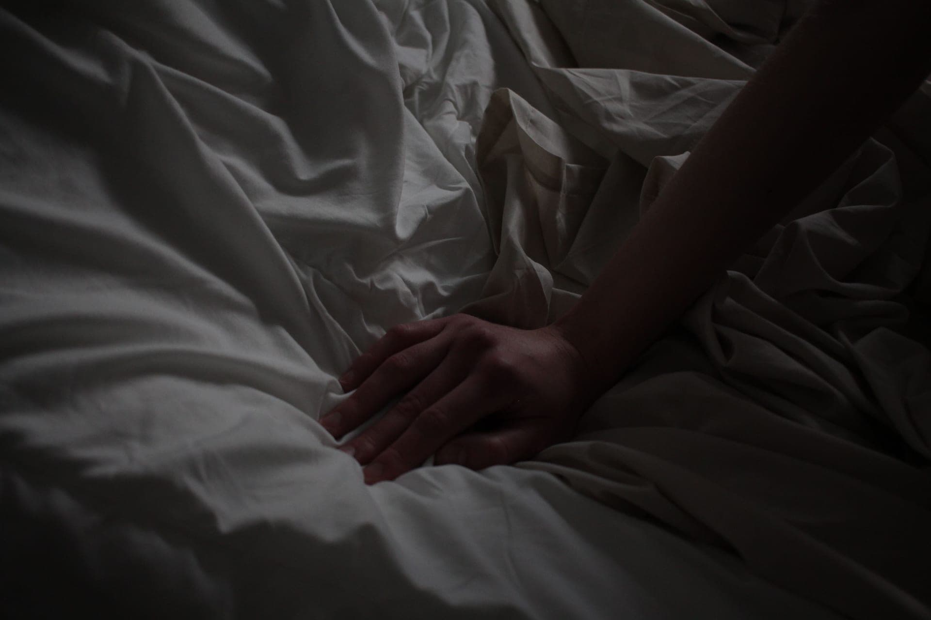 A darkened bedroom at night with rumpled sheets and low light