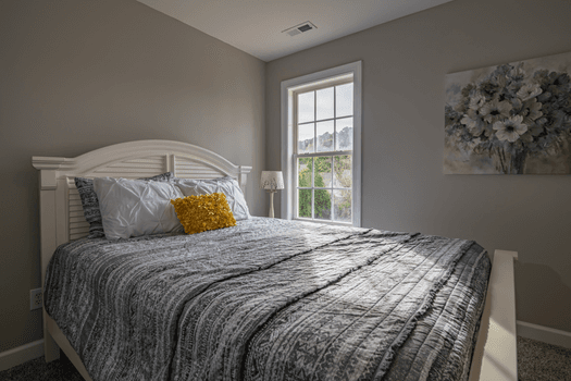 A bedroom with a double-hung window open on a summer afternoon