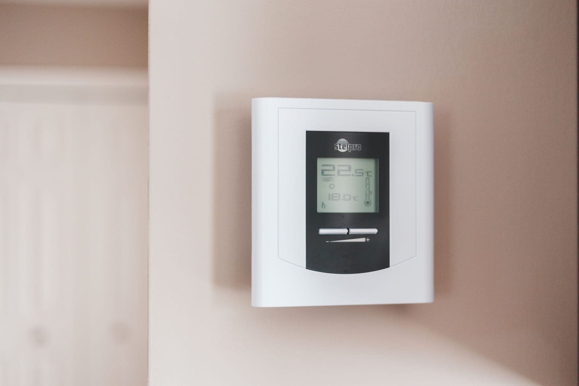 A digital thermostat mounted on a wall showing a temperature setting