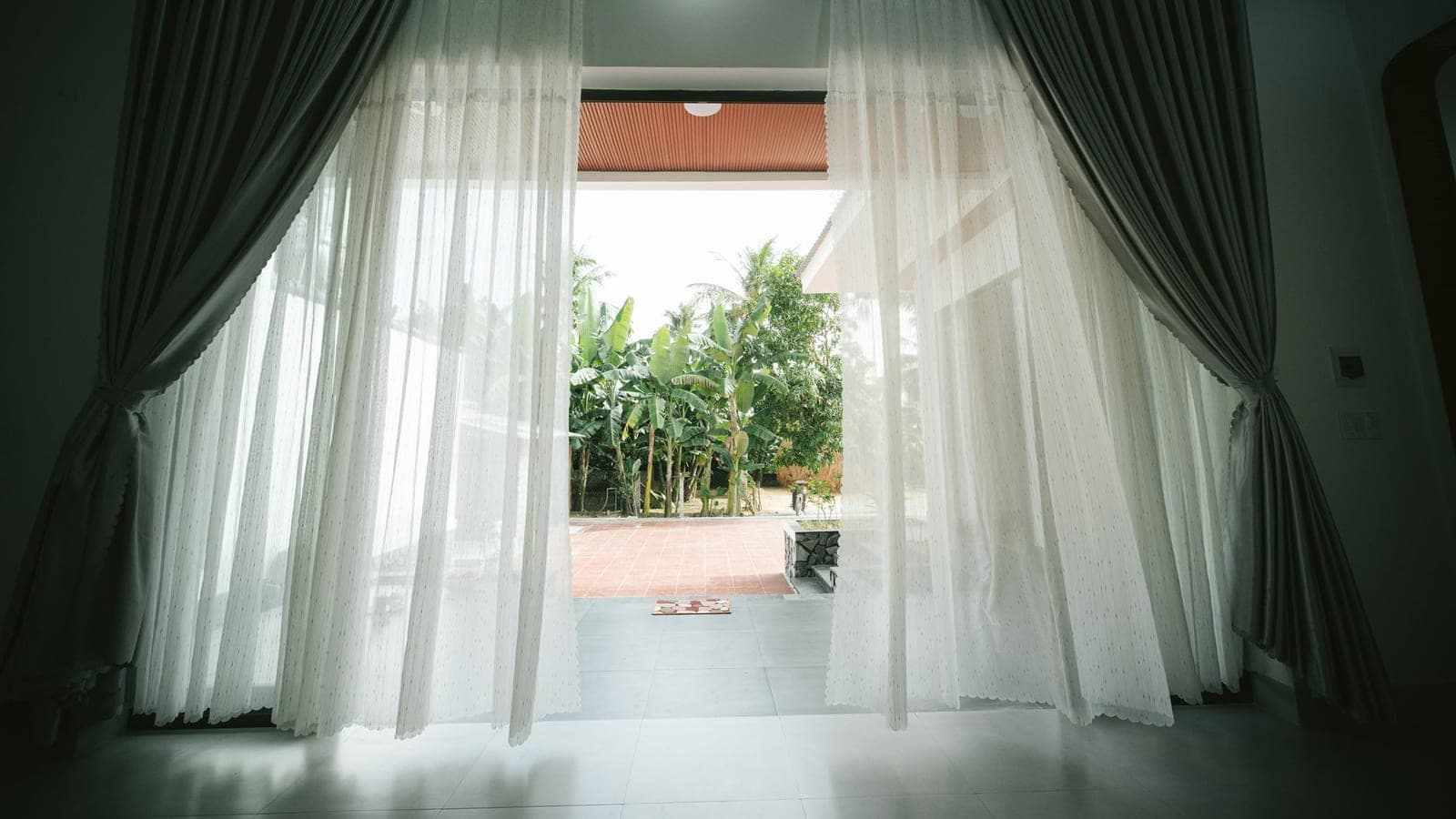 An open window with a curtain moving in the breeze