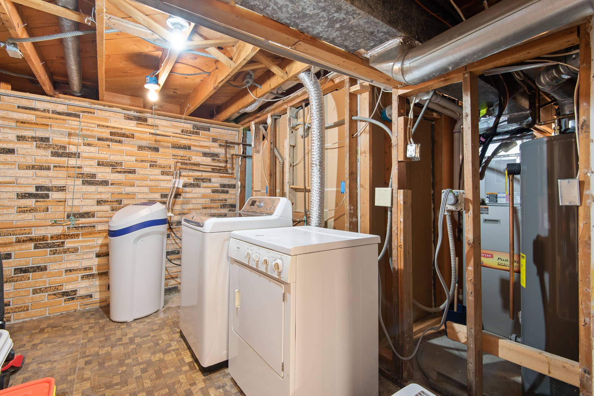 A basement utility room with exposed brickwork and laundry appliances